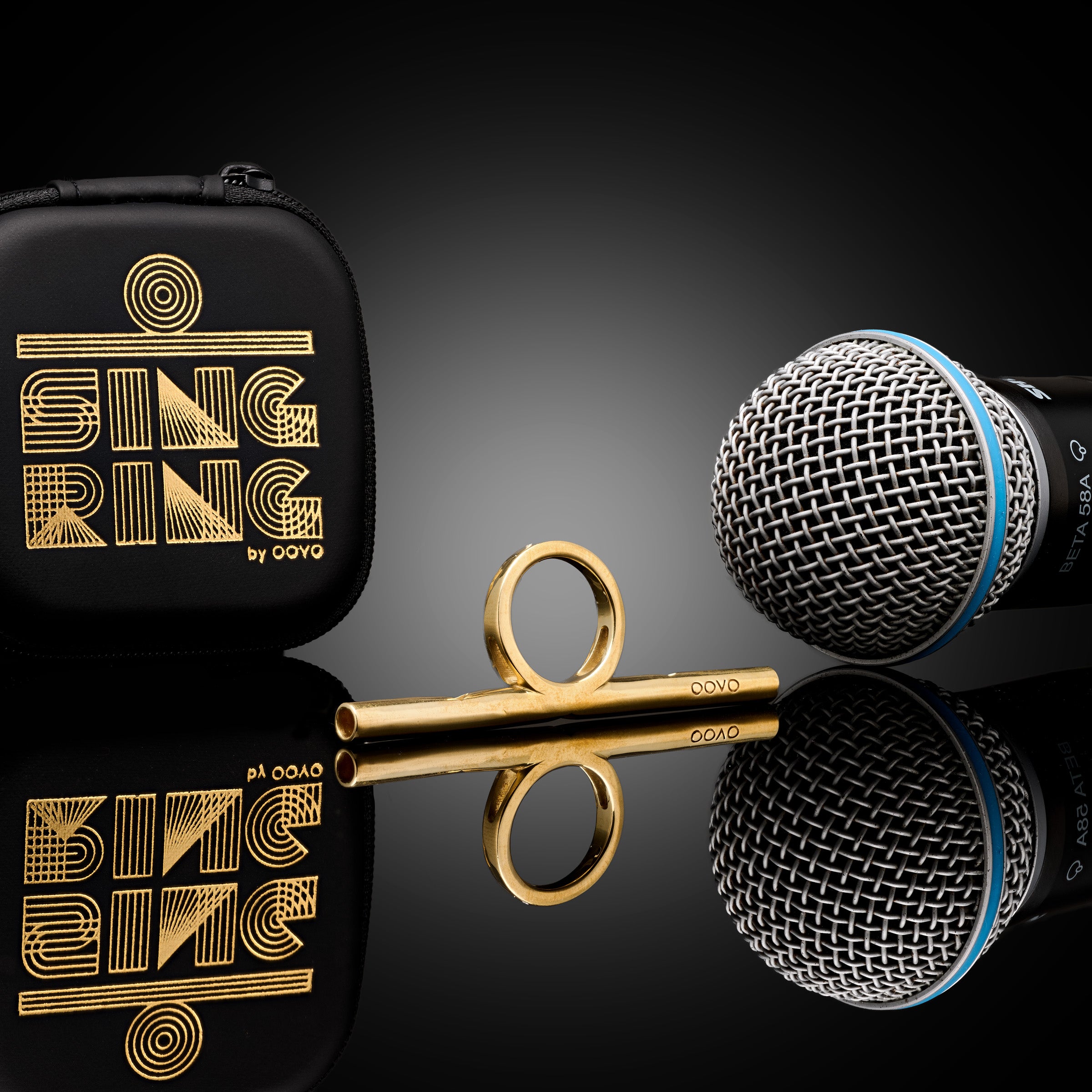 OOVO Sing Ring — gold straw with its black zip case and a microphone on dark reflective glass.