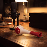 Breather Voice respiratory trainer lying on a recording-studio desk beside a condenser microphone.