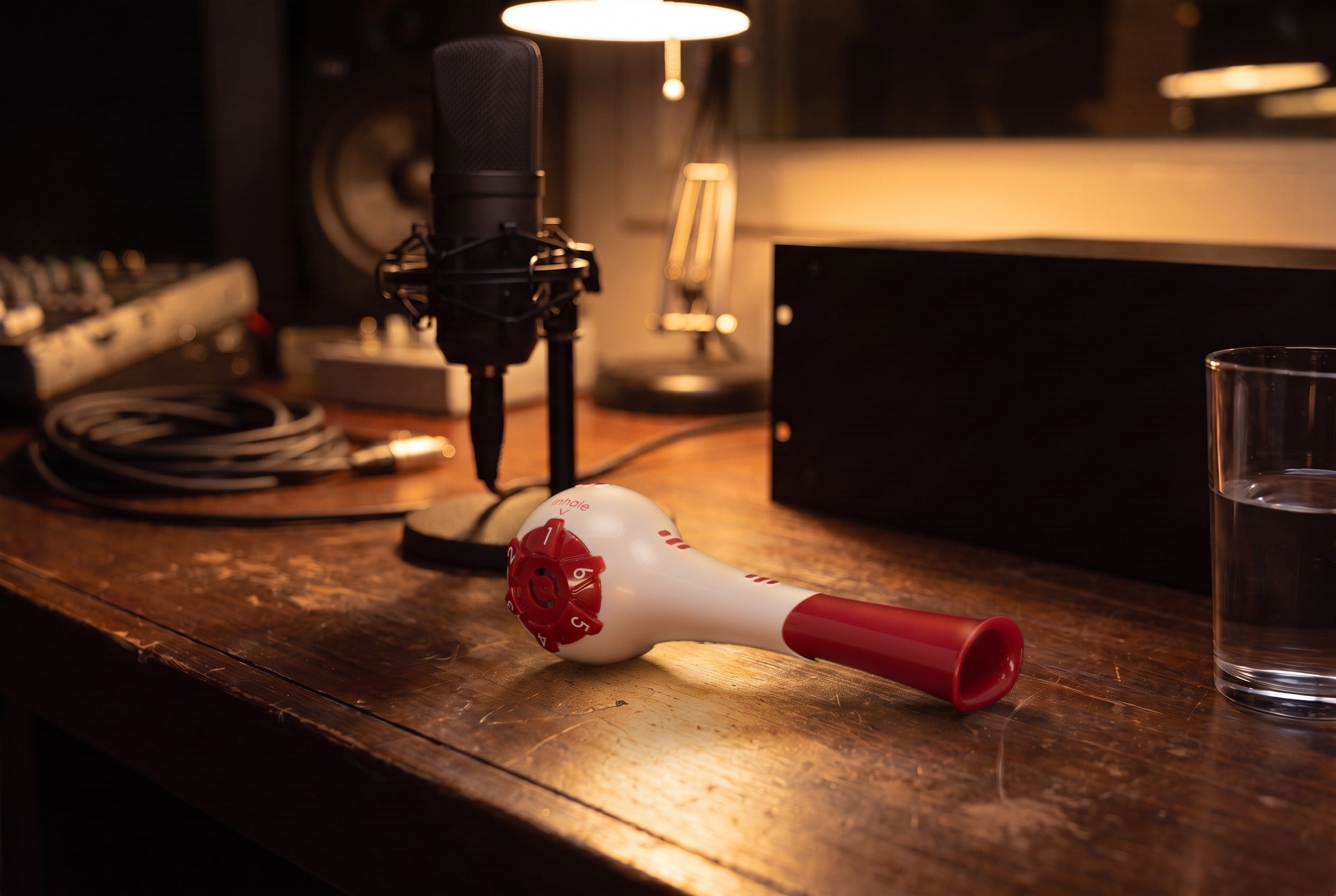 Breather Voice respiratory trainer lying on a recording-studio desk beside a condenser microphone.