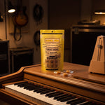 Vocal Eze Lemon Drops pouch on an upright piano beside a metronome, wrapped drops nearby.