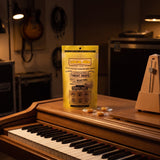 Vocal Eze Lemon Drops pouch on an upright piano beside a metronome, wrapped drops nearby.