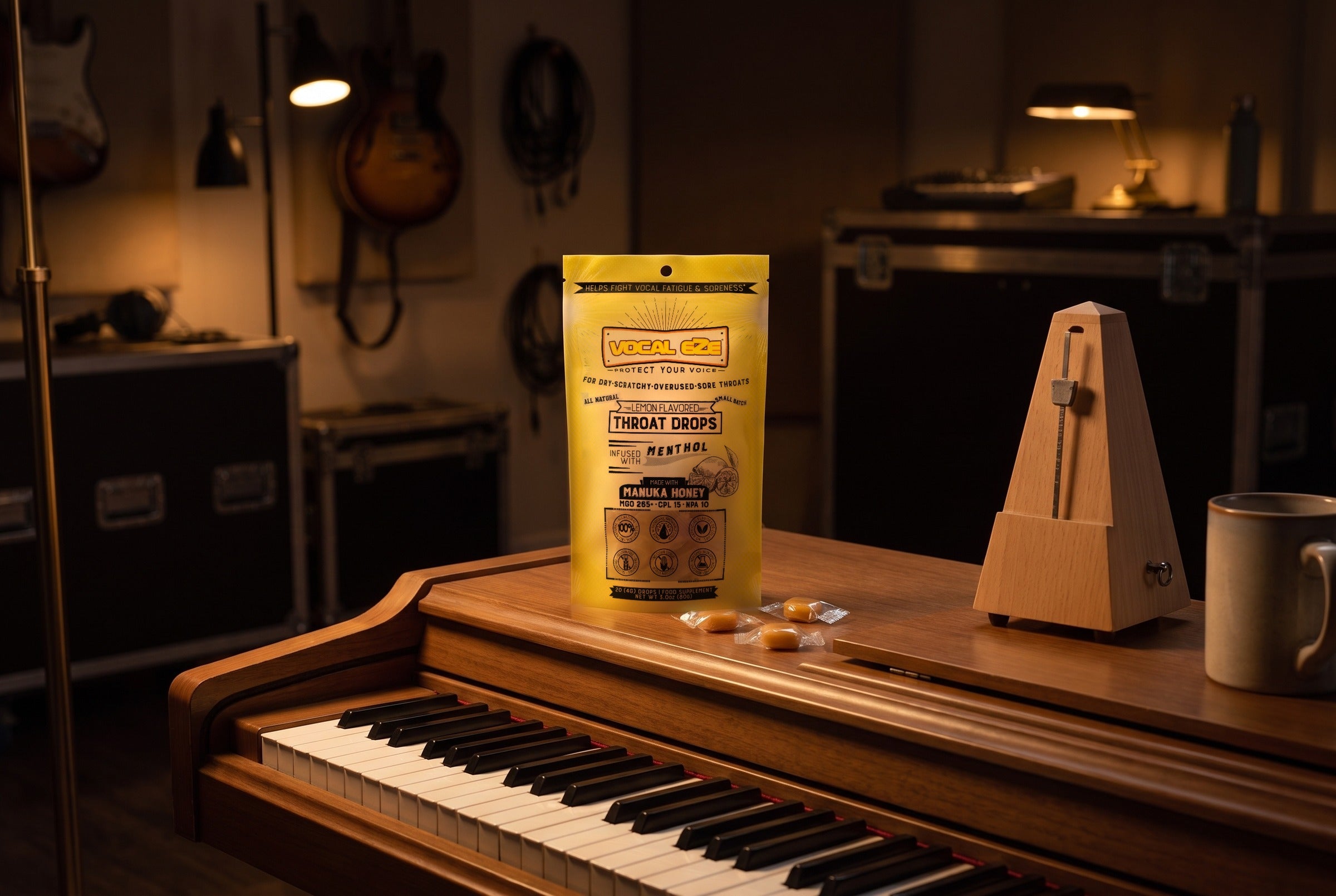 Vocal Eze Lemon Drops pouch on an upright piano beside a metronome, wrapped drops nearby.