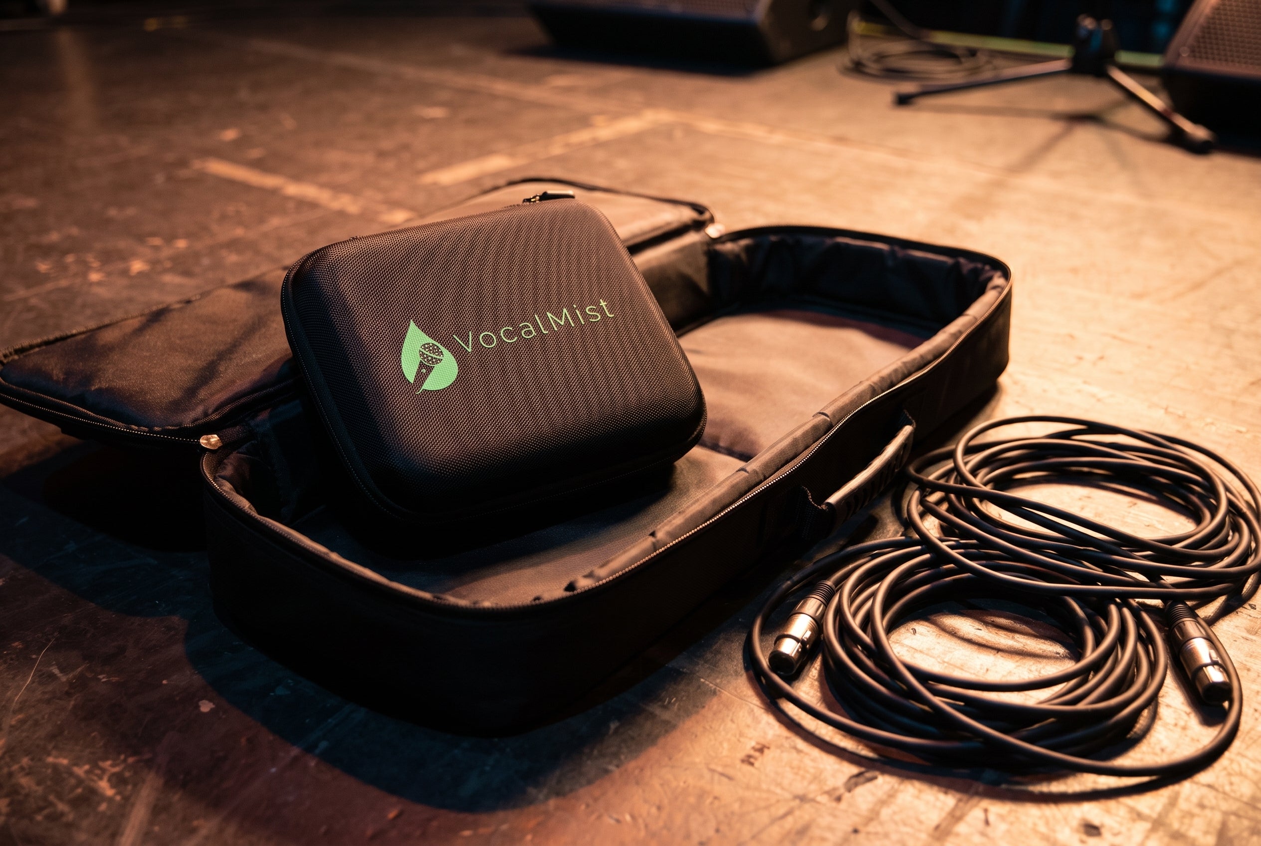 VocalMist carrying case on an open gig bag backstage with coiled XLR cables.