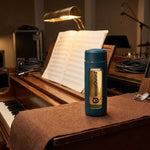 VocalGuard glass bottle on a piano-top felt runner in a rehearsal room.