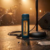 VocalGuard glass bottle on stage beside a microphone stand at soundcheck.
