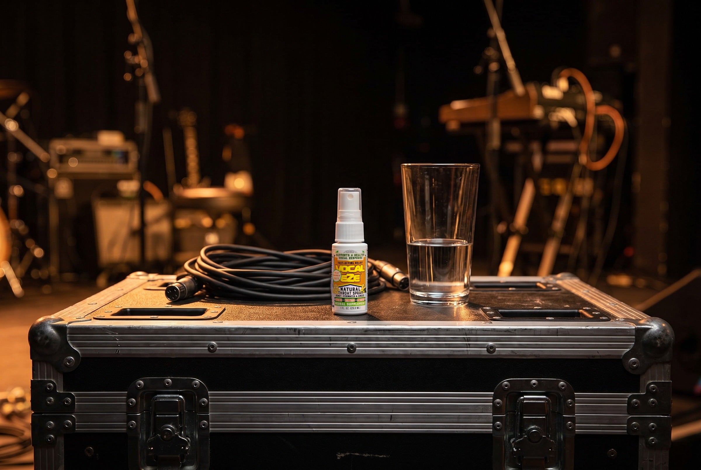 Vocal Eze Throat Spray standing on a road case backstage with a coiled cable.