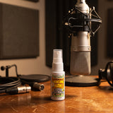 Vocal Eze Throat Spray on a voice-over booth desk beneath a condenser microphone.