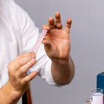 VocalMist Hydration Formula — holding a single saline vial between fingers.