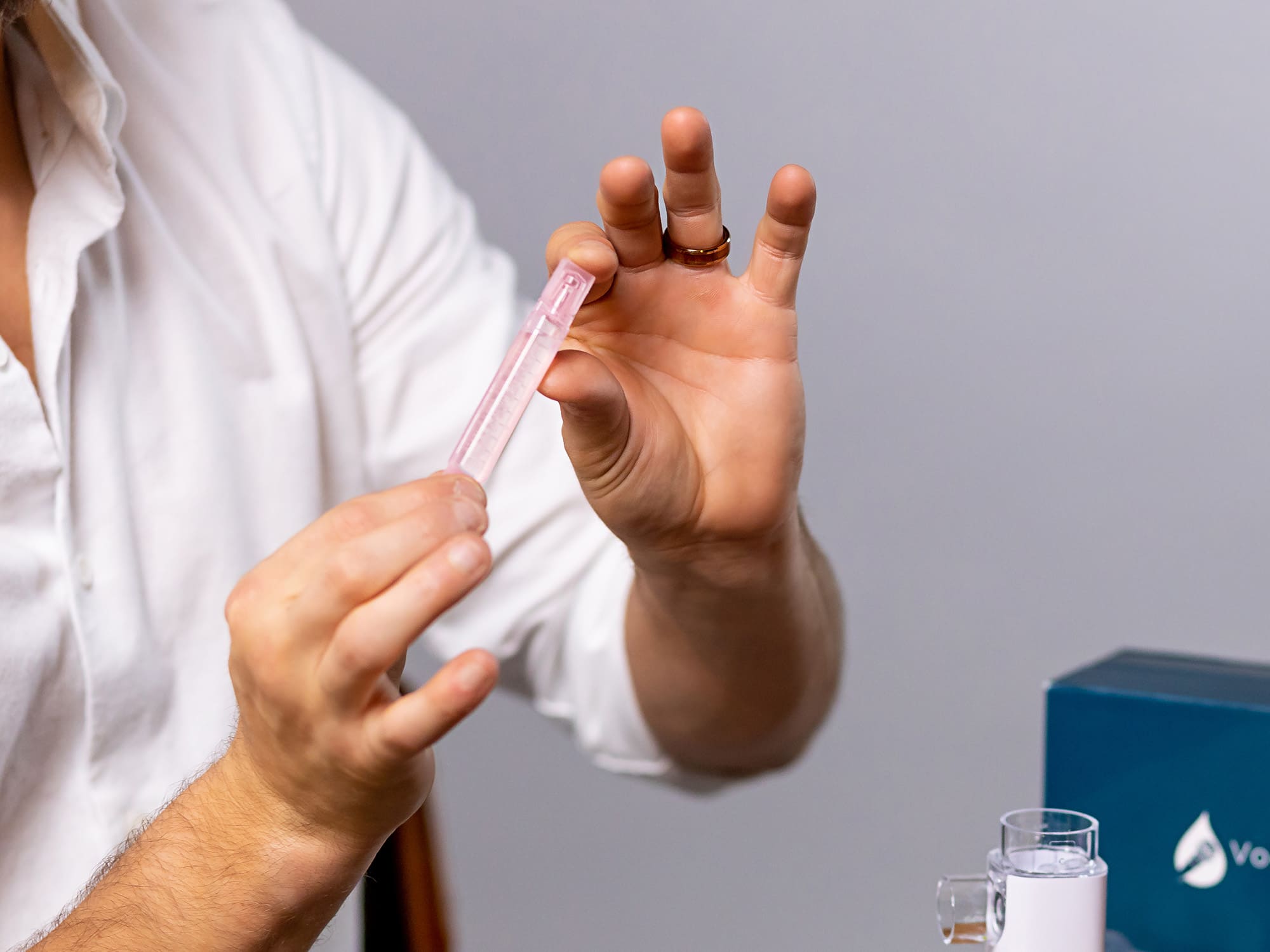 VocalMist Hydration Formula — holding a single saline vial between fingers.