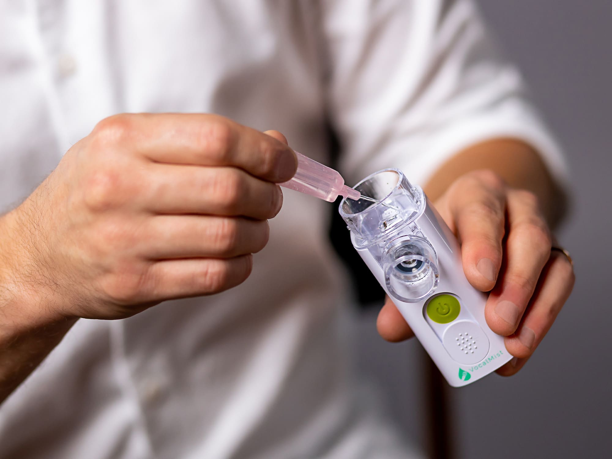VocalMist Hydration Formula — squeezing a saline vial into the nebulizer's medication cup.