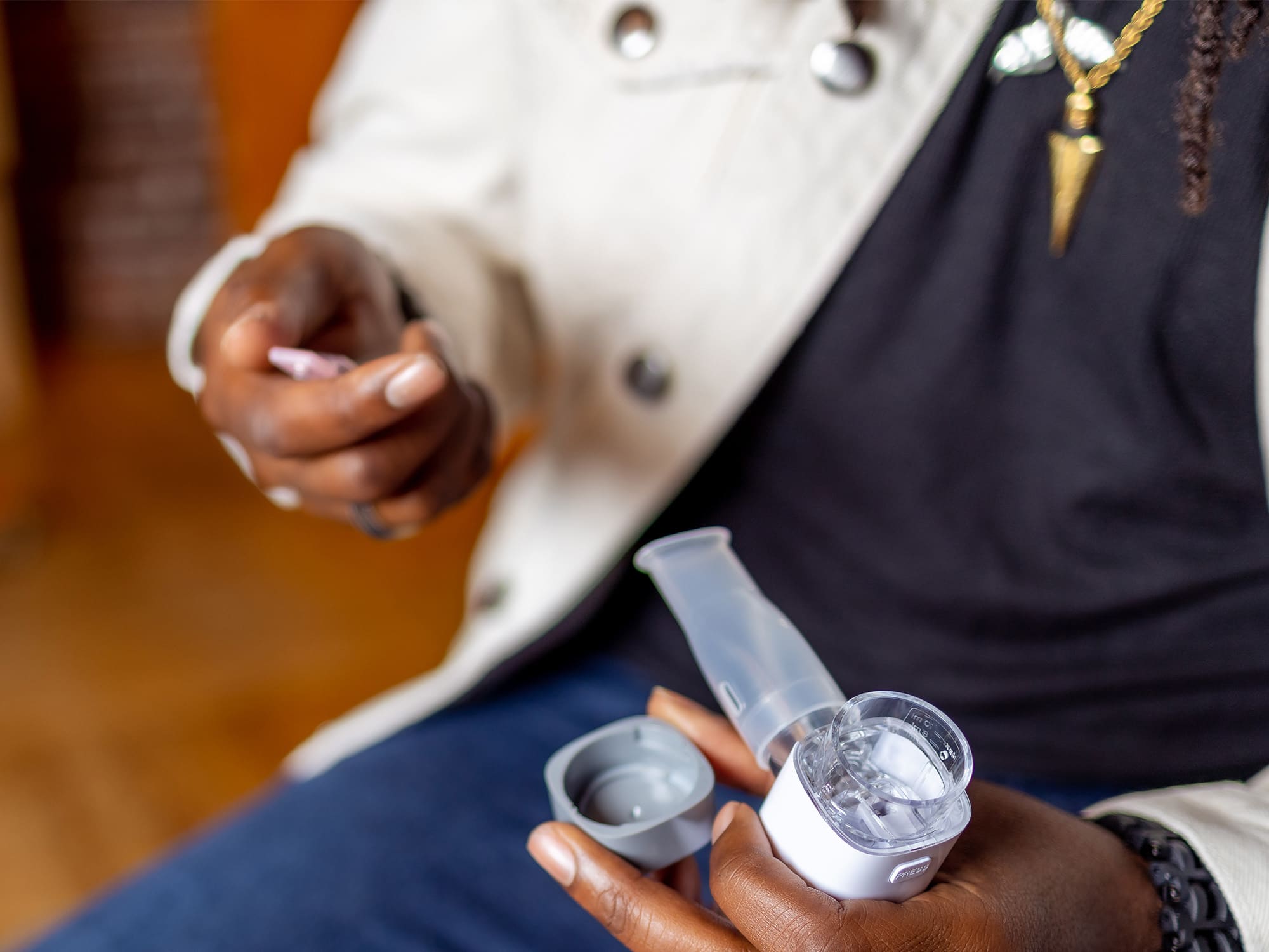 VocalMist Hydration Formula — opening a saline vial over the nebulizer's mouthpiece and cap.