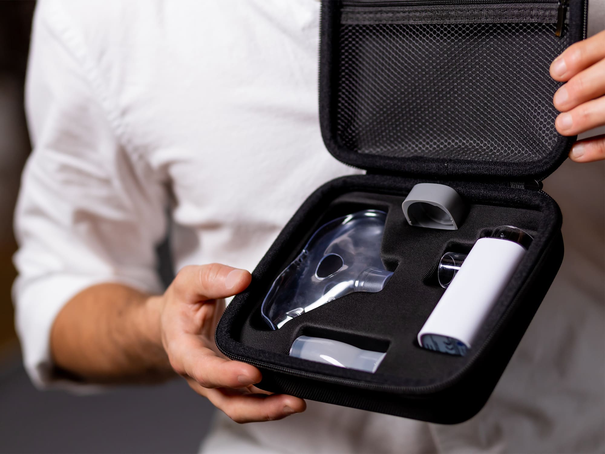 VocalMist Carrying Case — open case held in hands, showing the nebulizer and accessories in the foam insert.