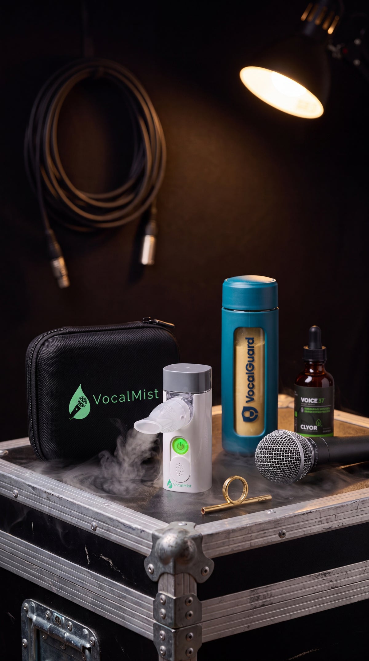 VocalMist portable nebulizer misting on a road case beside VocalGuard, VOICE37, and a microphone, backstage